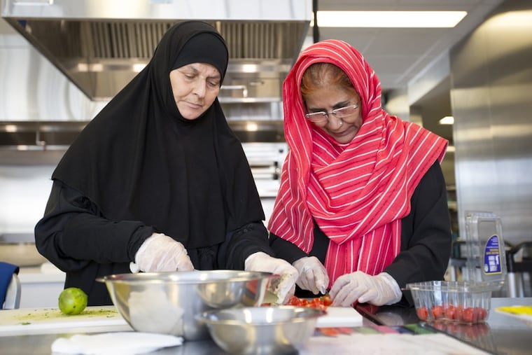 Sameerrah Saved Aldaraji (left), of Iraq, cuts bread with Nilofar Rauf, of Pakistan, at the Culinary Literacy Center at the Free Library of Philadelphia.