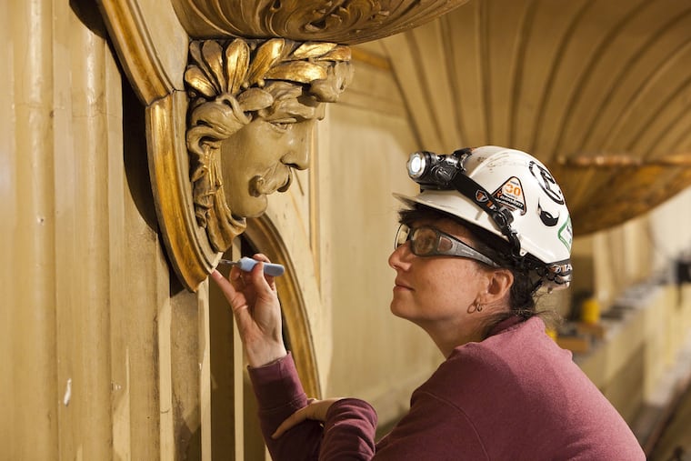 A woman works on the facade of the Wanamaker Organ, recently restored at Macy's in Center City.
