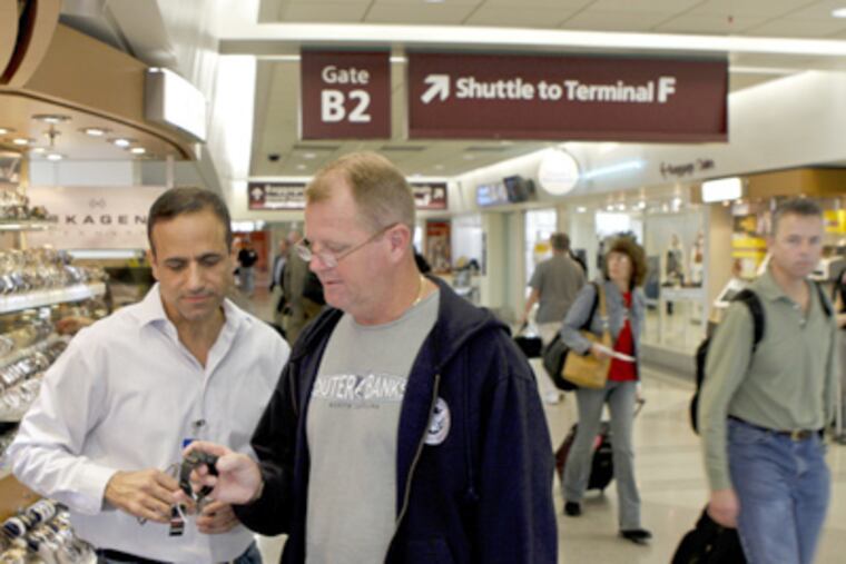 Ben Cohen (left), owner of the Time to Fly kiosk at Philadelphia International Airport, shows Shawn McElroy a watch. (Michael S. Wirtz / Staff Photographer)