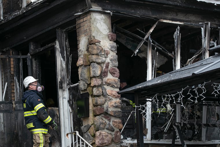 A Philadelphia firefighter assesses the damage at the scene of a fire early Saturday morning in West Oak Lane that killed a man and a woman and left a teenager hospitalized.