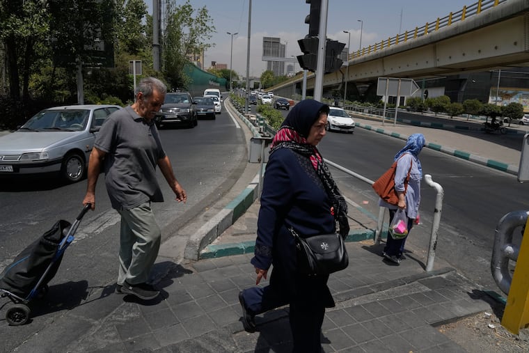 People cross a street in Tehran, Iran, Tuesday, July 21, 2026.
