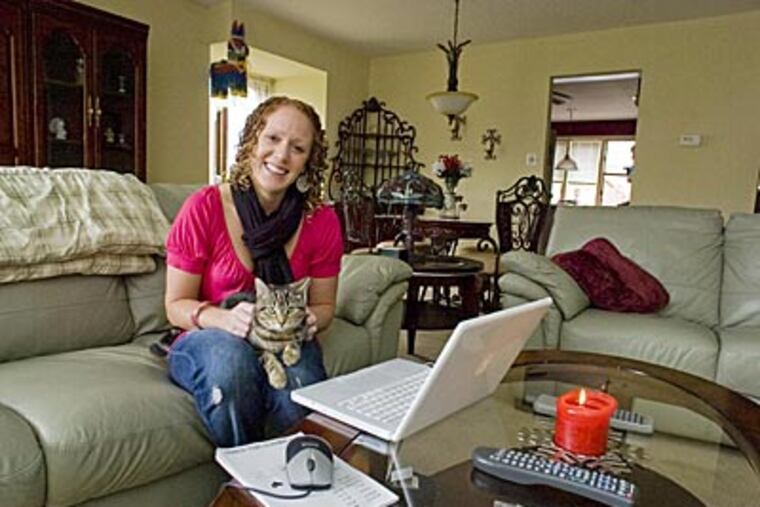 Jennifer Aglira, 28, and her cat Gypsy, are looking for roommates to help defray the costs of her condo in the Andorra section of Philadelphia. ( Clem Murray / Staff Photographer )