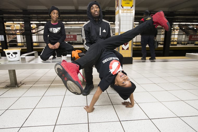 Jayden Thompson, 8, does one of his moves as he waits with sister Tyanna, 10, and father, Donnie for a subway train on Nov. 10, 2018. CHARLES FOX / Staff Photographer