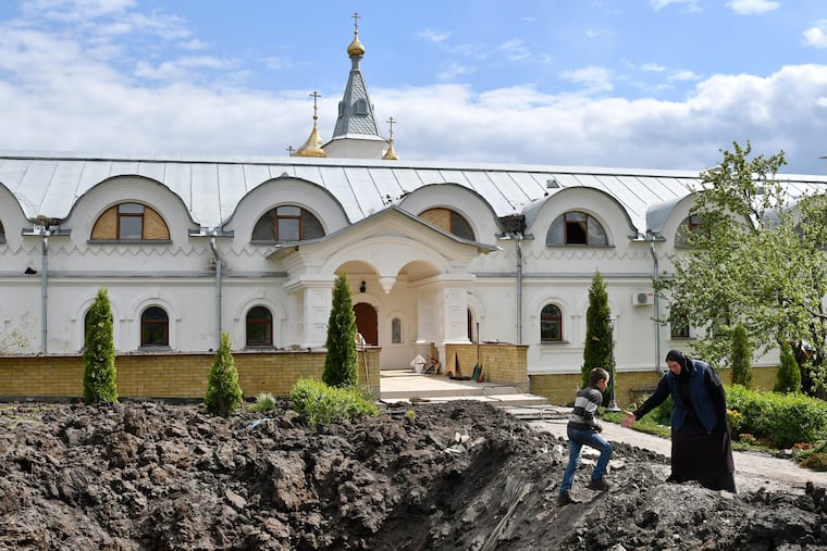 Orthodox Sister Evdokia, right, helps Maxim to come up from the crater of an explosion, after Russian shelling next to the Orthodox Skete in honor of St. John of Shanghai in Adamivka, near Slovyansk, Donetsk region, Ukraine.