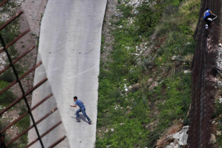 In this July 28, 2011 file photo, two men illegally cross the border fence separating Nogales, Ariz., and Nogales, Sonora, Mexico. The Supreme Court agreed Monday, Dec. 12, 2011 to rule on Arizona's controversial law targeting illegal immigrants. The justices said they will review a federal appeals court ruling that blocked several tough provisions in the Arizona law. One of those requires that police, while enforcing other laws, question a person's immigration status if officers suspect he is in the country illegally. (AP Photo/Jae C. Hong, File)