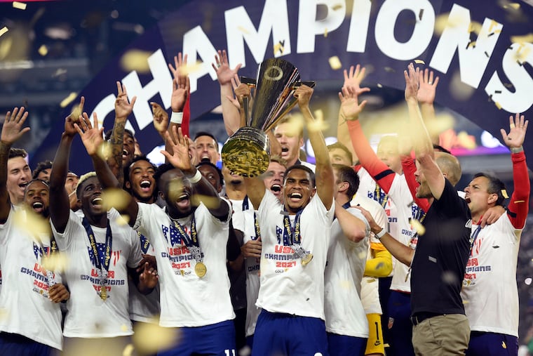 Reggie Cannon, center, hoists the trophy as the United States celebrates beating Mexico in the Gold Cup final.