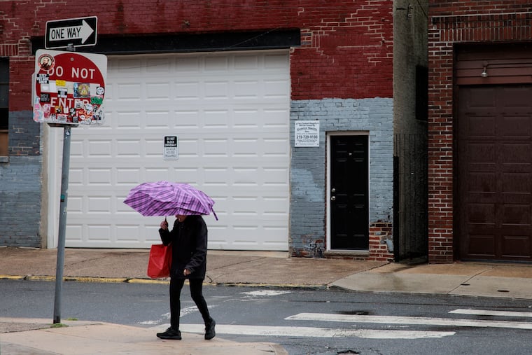 A pedestrian braves the rain in South Philly last month. Downpours were expected Monday.