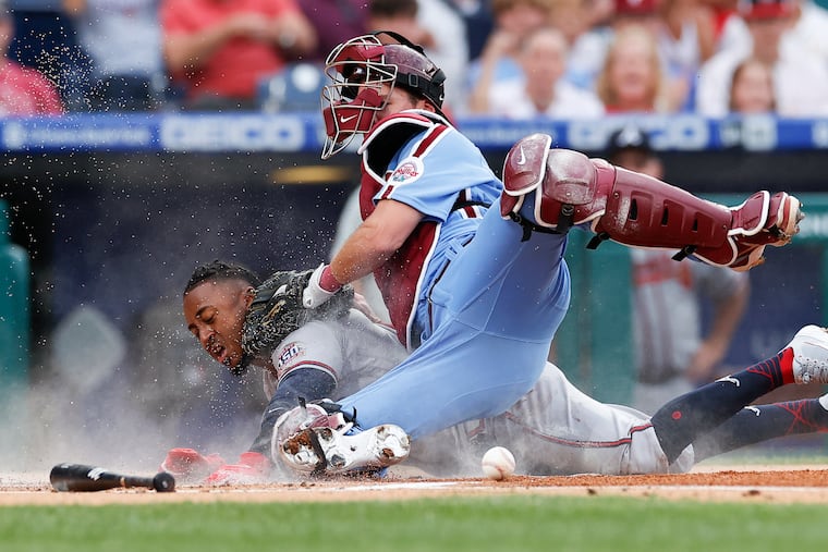 Atlanta Braves second baseman Ozzie Albies slides safely into home plate as the ball squirts away from Phillies catcher Andrew Knapp in the first inning Thursday night at Citizens Bank Park.