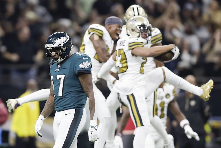 Alshon Jeffery walks past the Saints' Marshon Lattimore, Justin Hardee and Marcus Williams celebrating Lattimore's first-quarter interception of Carson Wentz.