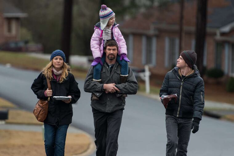 Maria Bello (left), Hugh Jackman (carrying Erin Gerasimovich), and Dylan Minnette star in the violent thriller "Prisoners."
