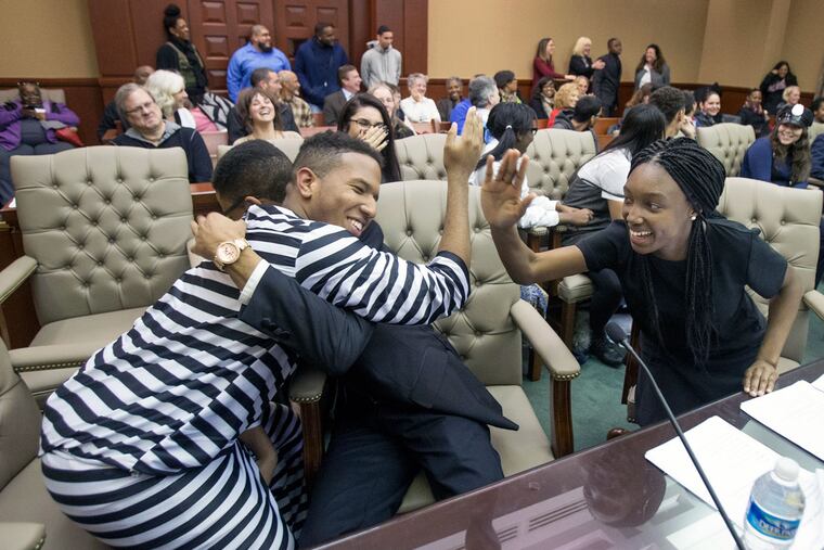 Darwin Guzman (left), playing the accused, celebrates with his defense team — Stephen Young and Jamira Greene — after the verdict of “not guilty” in the mock trial in Camden.