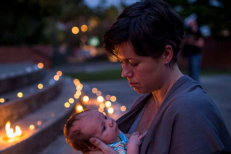 Kate Lemoine holds her daughter, Harlan Hawkins, during a vigil for the victims. PAUL KIEU / (Lafayette, La.) Daily Advertiser