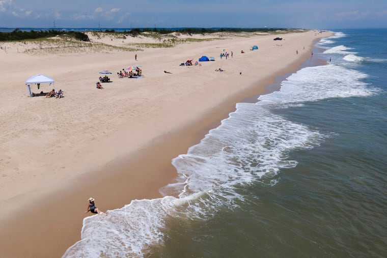 Waves crash near a beachgoer in 2022 in Rehoboth Beach, Del.