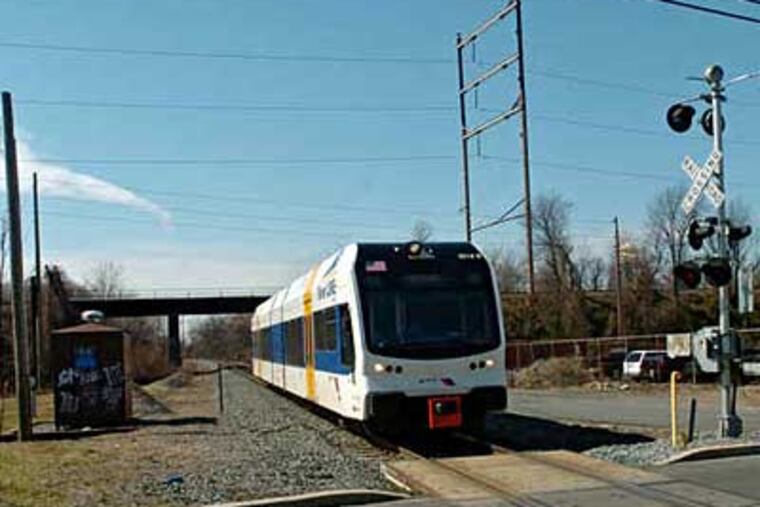 A River Line light rail-train bound for Trenton passes under the trestle in Pennsauken used by Amtrak's Atlantic City Line, near the crossing at Derousse and Zimmerman Avenues.
