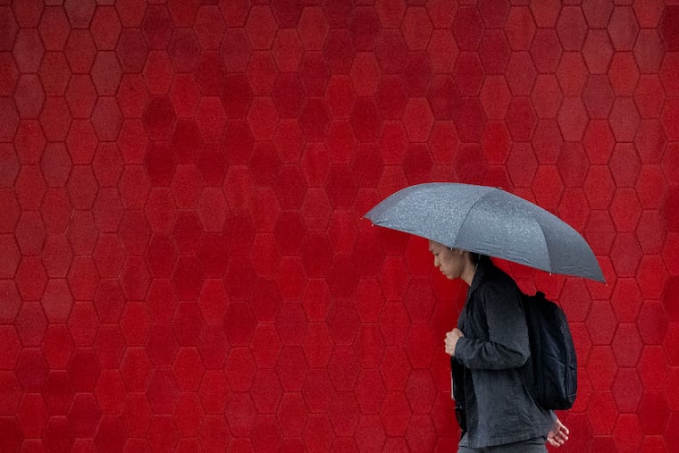 A pedestrian shields himself from the rain with an umbrella as he walks along the 1800 block of Chestnut Street during a light rain.