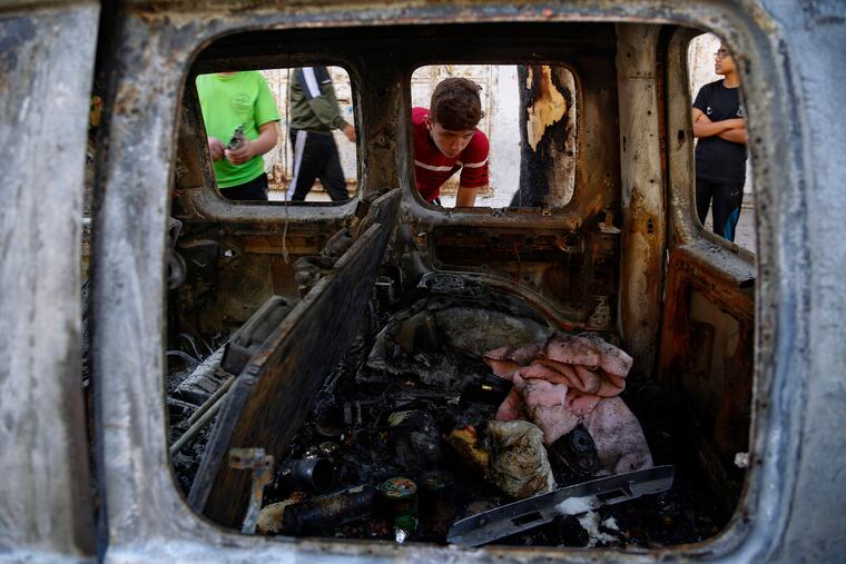 Palestinian kids look at a destroyed car after it was hit in an Israeli airstrike in Gaza City on Wednesday.