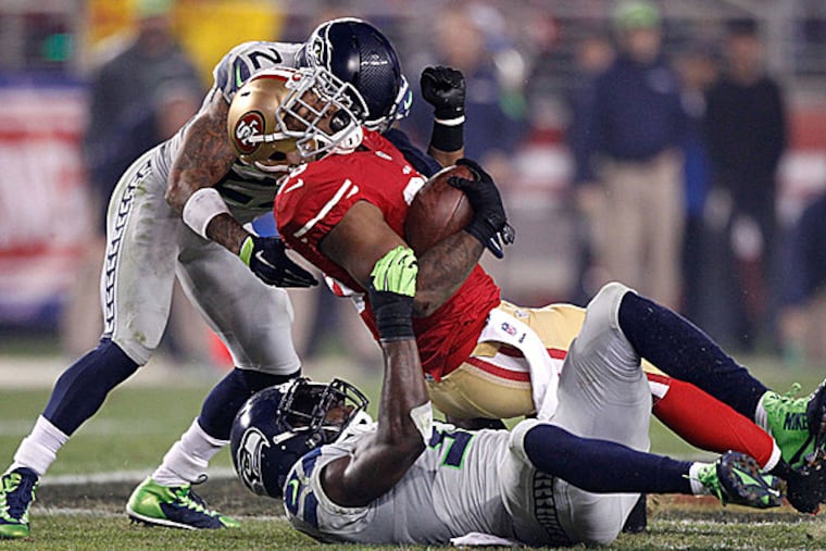 49ers running back Carlos Hyde is tackled by Seahawks safeties Earl Thomas and Kam Chancellor. (Cary Edmondson/USA Today Sports)