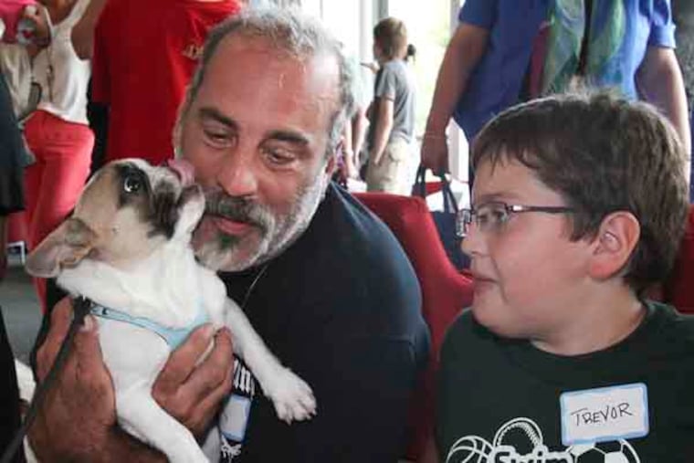 Erik Larys and his son Trevor Larys, 11 from Morganville, NJ meets Lentil, a small Philly bulldog who is a Facebook star because of his cleft palate and subsequent surgery, will ratchet up his public outreach Wednesday, visiting kids from Children's Hospital who have had -- or will have -- surgery like his. Penn's Vet complex, Wednesday, July 17, 2013. ( Steven M. Falk / Staff Photographer )