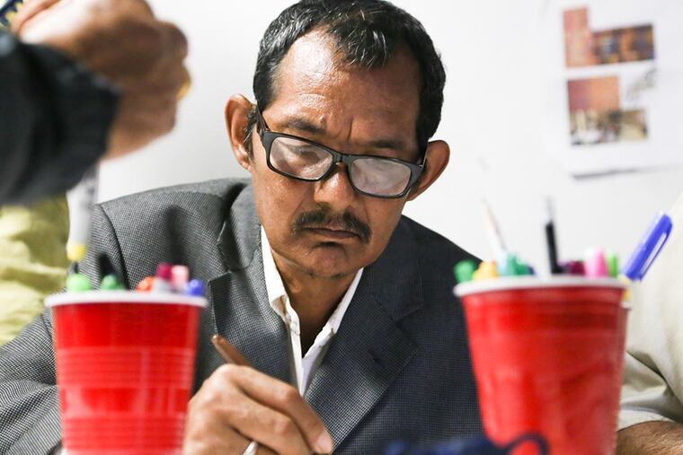 Mongal Tamang, a Bhutanese refugee of Nepali descent, outlines in marker a part of a sketch for a mural showing the journey of refugees from Bhutan to refugee camps in Nepal. (Andrew Thayer / Staff Photographer)
