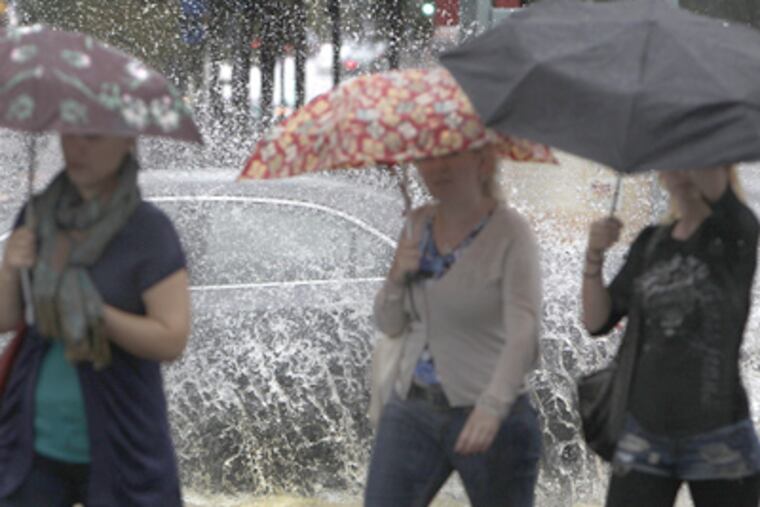 Umbrellas were up as rain came down at Fifth and Market Sts. A car splashed through the intersection during the drenching. (David Maialetti / Staff Photographer)
