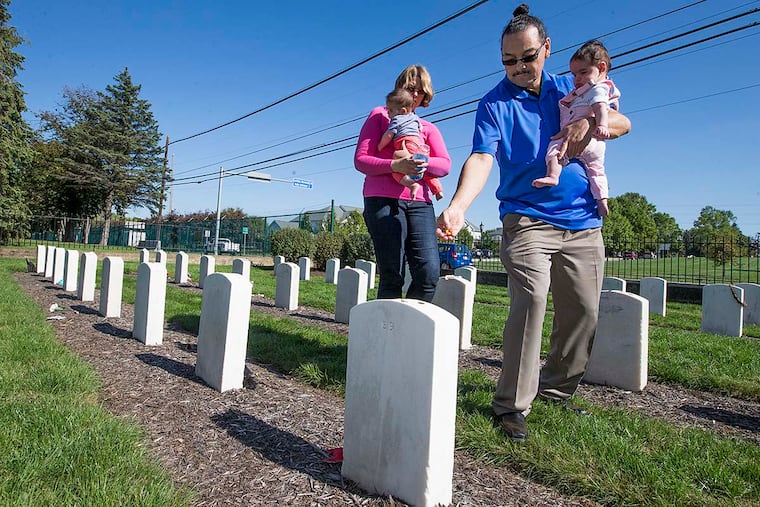 Anna Naruta-Moya, left, with Oku, and Daniel Moya, right, with Makowa, sprinkle candies on the graves at the Indian Cemetery. Daniel's great-grandfather, Antonio Tapia, had attended the Carlisle school and graduated in 1901. Daniel and Anna are working on a Museum of Indian Arts & Culture project to help people, primarily those from the 23 New Mexico tribes and the Hopi people, access federal records never before available in New Mexico.