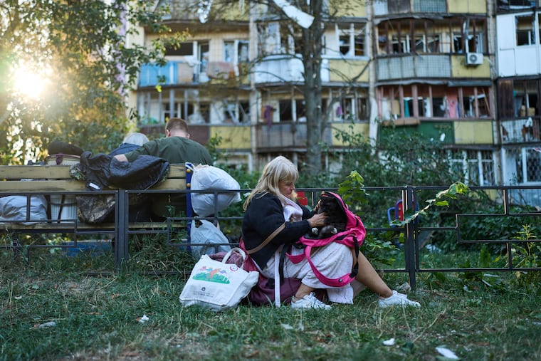 Local residents sit in front of heavily damaged residential buildings Thursday after an overnight Russian attack in Kyiv, Ukraine.