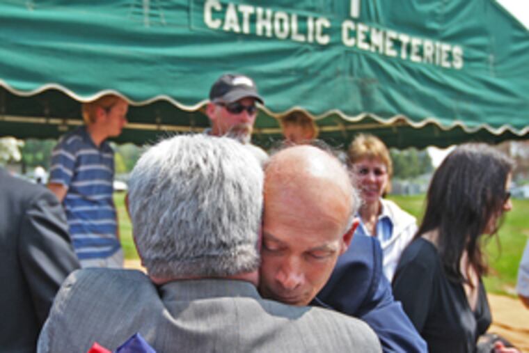 Joe Crescenz, brother of Medal of Honor winner Michael Crescenz, embraces a family friend at a ceremony marking his sibling's disinterment from Holy Sepulchre Cemetery for a move to Arlington National Cemetery this month. He holds a flag given to him by a Vietnam veteran.