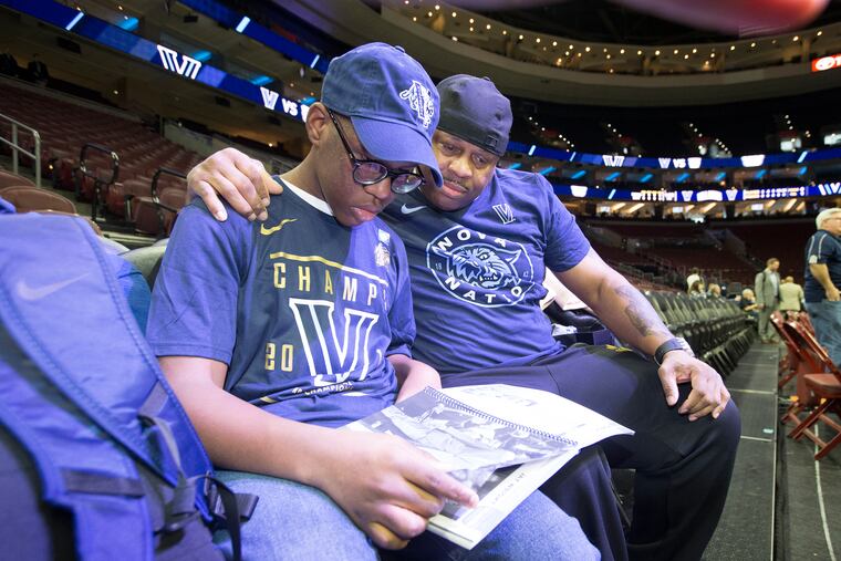 Kyle Tucker (left) and Deputy Sheriff Mike Terry go through the Villanova media guide before the game at the Wells Fargo Center Saturday -- Terry's surprise gift to the teen after finding him lost and scared in January after he got on the wrong SEPTA bus home from school.