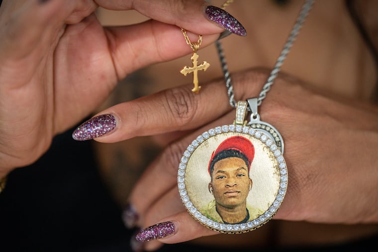 Teahnna Jeffrey, the mother of 16-year-old Calvin "CJ" Johnson, holds the cross he was wearing when he died and a necklace she had made with his photograph. Johnson was shot and killed by another teenager on June 9.
