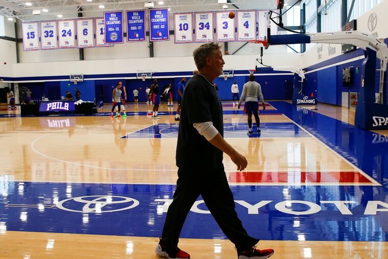 Sixers coach Brett Brown walks to meet the media after a practice at the team's training complex in Camden.