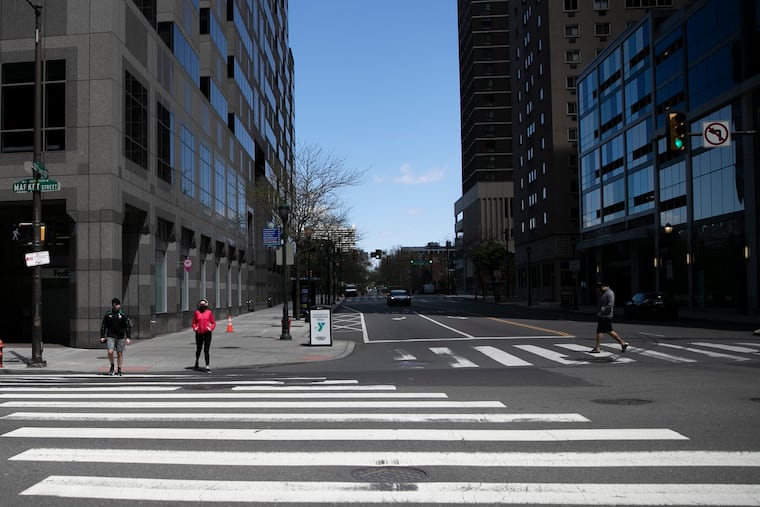 Pedestrians wait to cross the street at 20th and Market in Center City Philadelphia on Wednesday. Center City life has completely changed since the arrival of the coronavirus, with businesses shuttered and office buildings unoccupied.