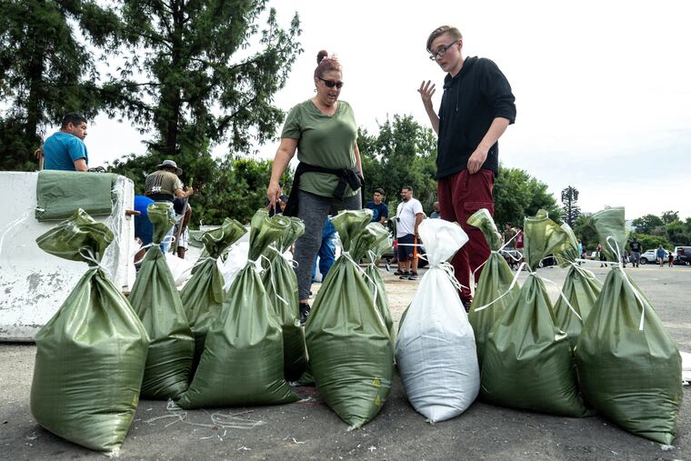 Rebecca Glaser and her son Jaden Fitzpatrick, 16, prepare to load sandbags at Wildwood Park in San Bernardino, Calif, on Saturday, as residents prepared for the arrival of Hurricane Hilary.