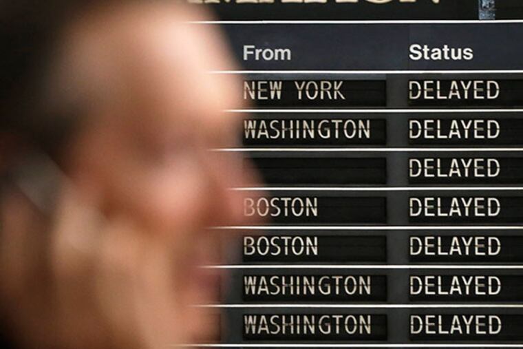 A passenger speaks on his phone as the train information board shows delays at 30th Street Station Wednesday, Sept. 11, 2013, in Philadelphia. Amtrak says train service between Philadelphia and Washington has been restored after being suspended because of damaged overhead wires. Spokesman Craig Schulz says passengers should expect delays as crews continue repairing the system and restoring the second track for service. (AP Photo/Matt Rourke)