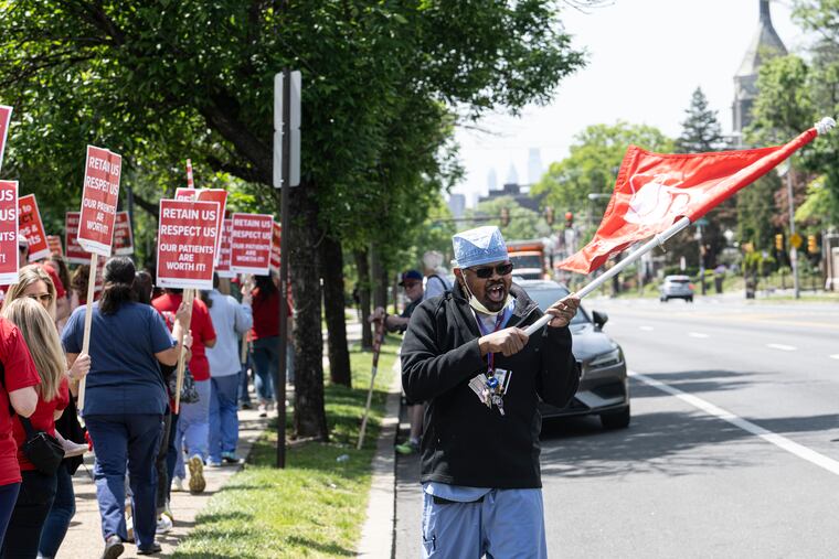 Einstein nurses approved a new contract on June 21. Patrick Campbell waves a flag during a rally along other health professionals on May 11 outside the Einstein Medical Center.