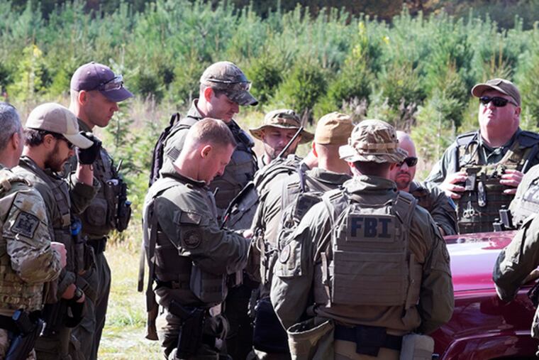 FBI agents gather for a briefing in a field during the continued search for Eric Frein on Wednesday, Oct. 8, 2014. ( ED HILLE / Staff Photographer )