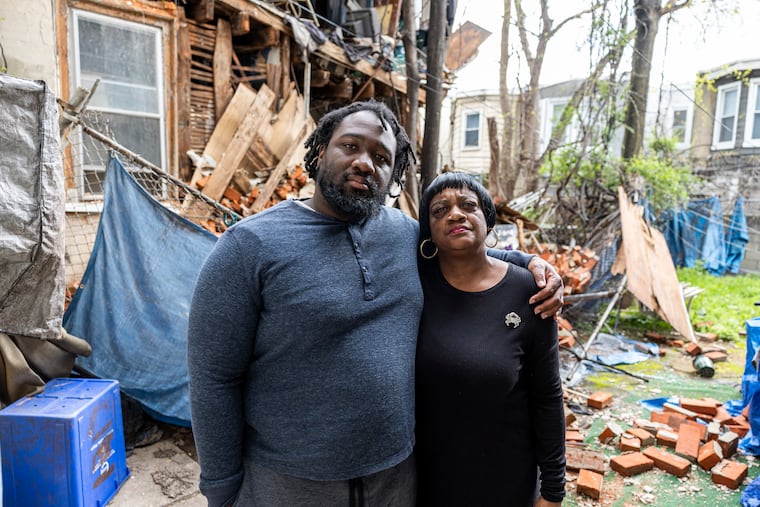 Sherrilyn Jackson and her son, Thomas Jackson, in their North Philadelphia backyard April 16, standing in front of debris that spilled onto their property following the collapse of the back of the house next door weeks earlier.