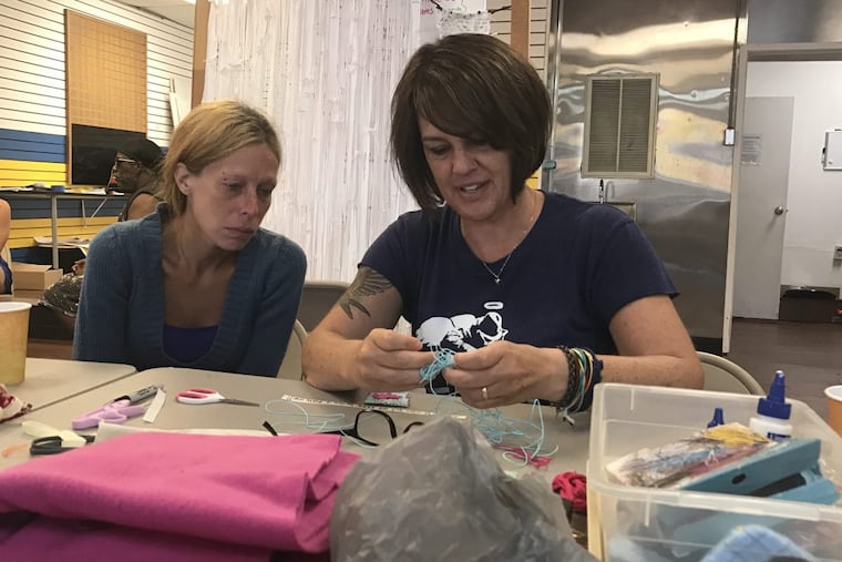 Holly (left), 36, from State College, Pa., works with Lisa Kelley, an artist who’s teaching workshops at the Kensington Storefront. .