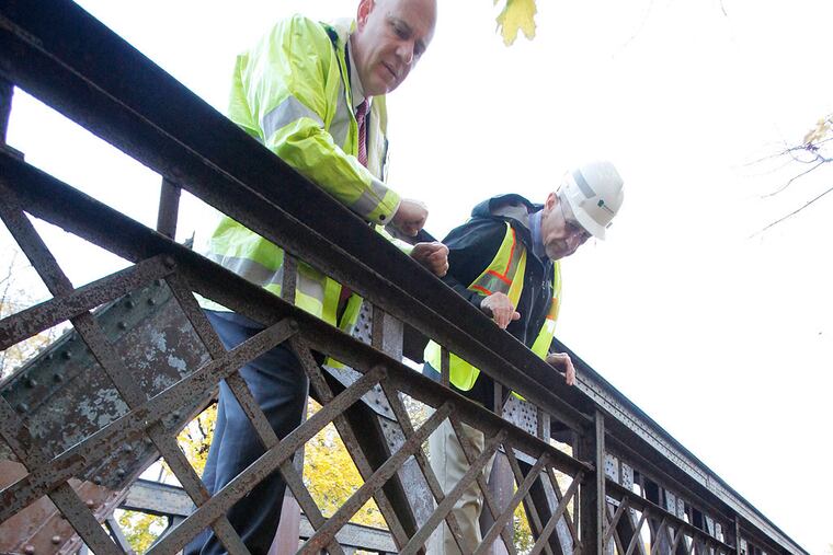 Jeffrey Knueppel, SEPTA Deputy General Manager Operations/EM&C Divisions, (left) and Lester Toaso, PENDOT District Executive Engineering District 6-o, (right) on the North Main St. bridge over Septa, exposed steel truss members along Main St. are experiencing extensive deterioration and corrosion. Also concrete that encapsulates the steel beams below the deck are deteriorated and corroded steel is exposed. This is a steel truss bridge on N. Main St. in Sellersville on November 7, 2013. ( ELIZABETH ROBERTSON / Staff Photographer )