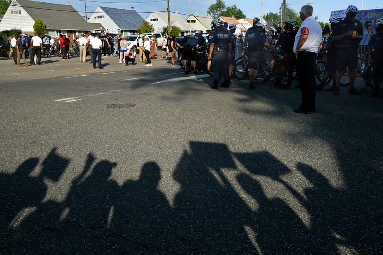 The shadows of supporters of President Trump and the police are cast in the street separating them from protesters in Northeast Philadelphia July 9, 2020 as Vice President Mike Pence appears at the nearby Fraternal Order of Police Lodge No. 5 for a "Back the Blue" rally