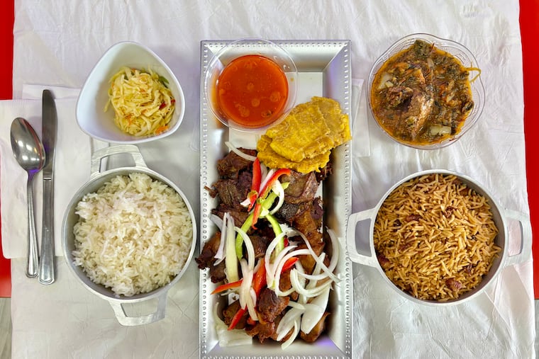 A Haitian feast at Gouté Creole includes a platter (center) of griot fried pork and goat with jus and fried plantains, and (clockwise from top left) pikliz slaw, legumes vegetable stew with beef, Haitian rice and beans and white rice.