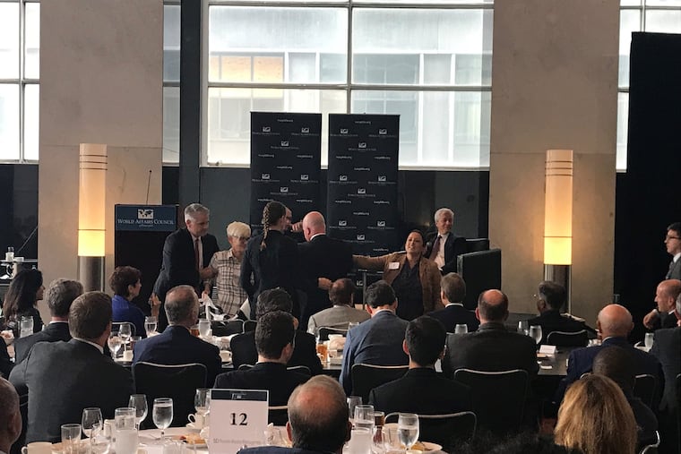 Jamie Dimon, at right of center, waits to resume his talk for more than 200 guests of the World Affairs Council Philadelphia, as security workers clear a handful of protesters who rushed up to the stage, in the Loews Philadelphia hotel, Sept. 24, 2018