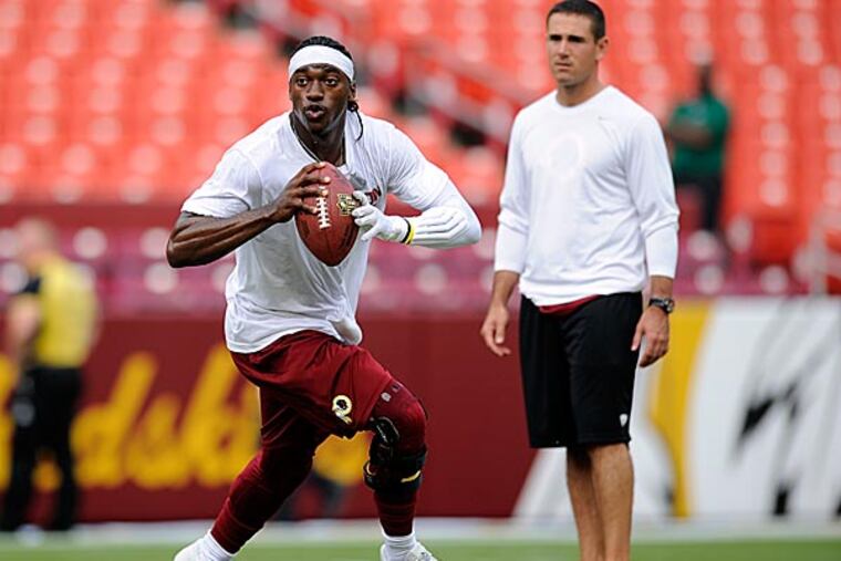 Washington Redskins quarterback Robert Griffin III runs on the field, with offensive coordinator Kyle Shanahan behind, during warm ups. (AP Photo/Nick Wass)