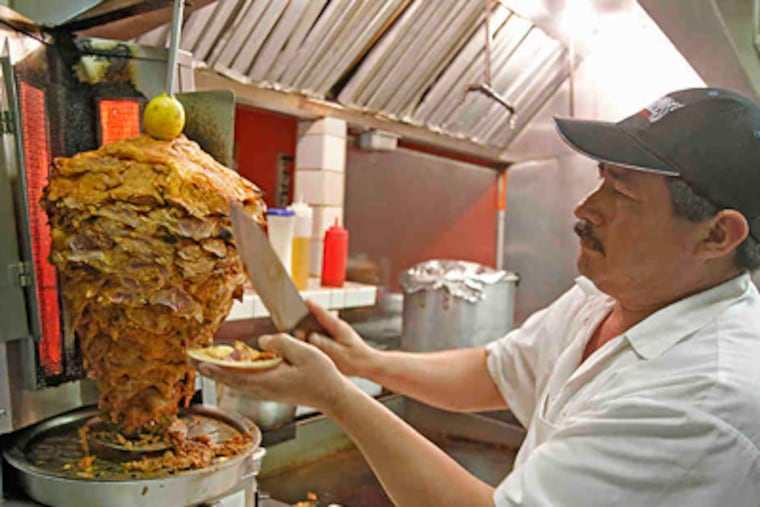 Los Taquitos de Puebla cook Evansto Torres slices pork from a trompo al pastor to make tacos al pastor. (Akira Suwa / Staff Photographer)
