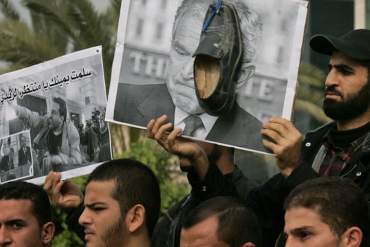 Palestinians in Gaza City, one holding a shoe and a picture of President Bush, attend a rally calling for Iraqi journalist Muntadar al-Zeidi's release.