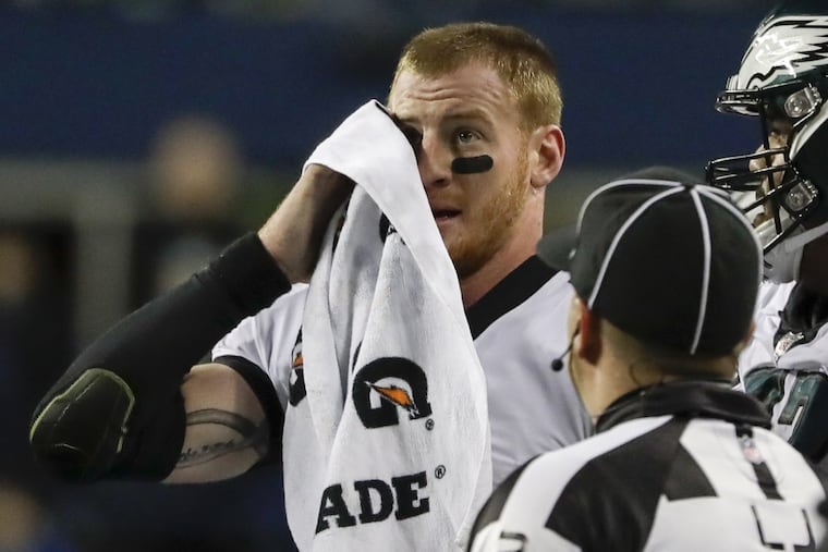 Eagles quarterback Carson Wentz wipes his face after fumbling the football just short of the end zone during the third quarter.