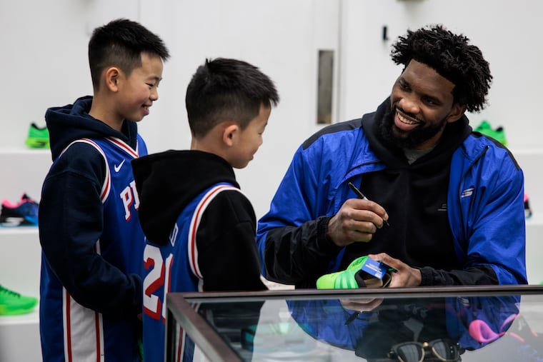 Joel Embiid signs autographs for Quentin Zheng, 10, left, and Mason Zheng, 9, center, during the release event for Embiid’s first signature shoe from Skechers, the SKX JE1, at Lapstone & Hammer on Wednesday.