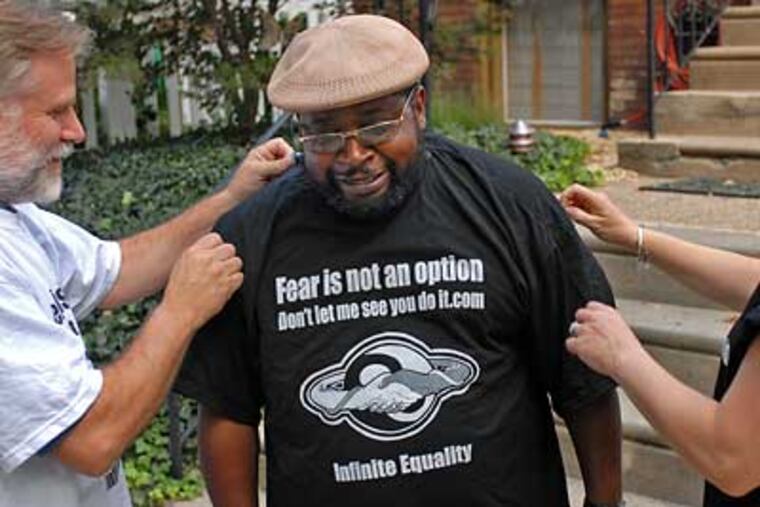 Darryl Hicks, a neighbor of Jeff Templeton, tried on one of Templeton's brand of "start snitchin'" T-shirts. (Tom Gralish / Inquirer)