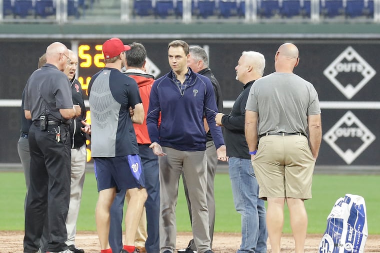 Phillies Vice President and General Manager Matt Klentak (center) talks to players and officials discuss field conditions before the Phillies and the Washington Nationals play on Monday, September 10, 2018. The game was called off and the two teams will play a double header tomorrow.
