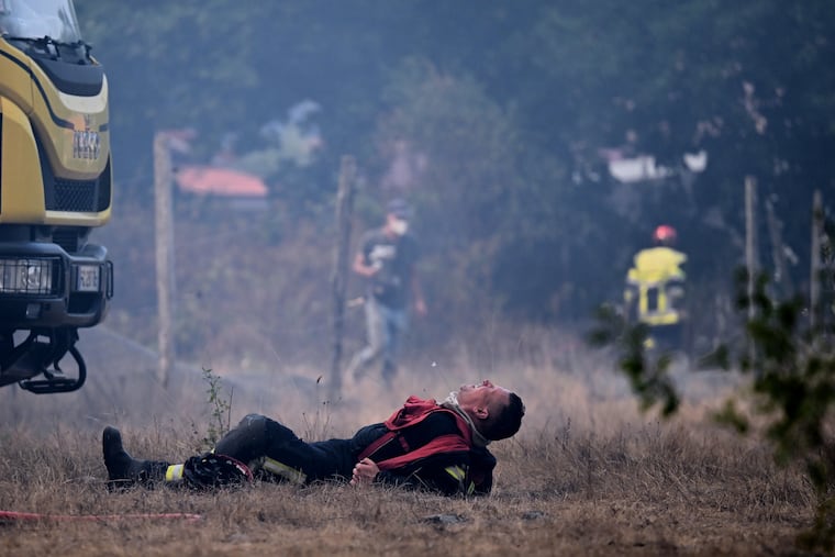 A firefighter lays on the ground after working to extinguish a fire in the forest near Blagon, during wildfires in southwestern France, Wednesday, July 29, 2026.