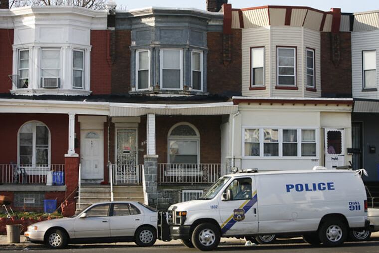 Philadelphia police sit on crime scene in the 5900 block of Cedar Street in West Philadelphia. The row house at left was the scene of the alleged home invasions.